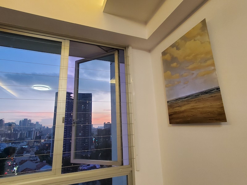 'Story of the Sea' by Stiliana Alexieva, pictured in Bernice's Singapore home. The painting is of the ocean horizon, with fluffy clouds and cool, still sea. 