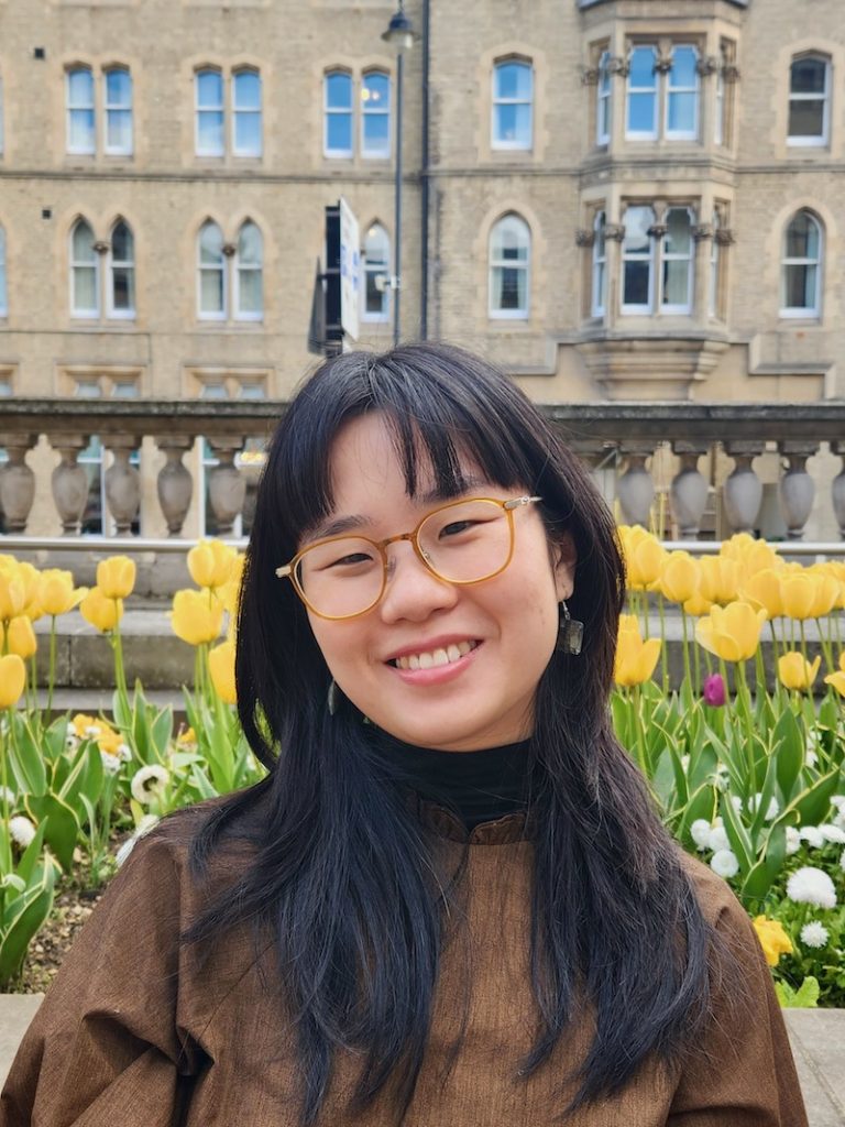 Old English architecture and yellow tulips are the backdrop of this portrait of Ping, our Operations Executive. 